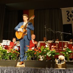 Der Bürgermeister steht auf der Bühne und hat seine Gitarre in der Hand