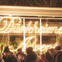 Der illuminierte Schriftzug mit der Aufschrift "Dürkheimer Advent" ist auf dem Ludwigsplatz angebracht und leuchtet den Weg zum Oberen Kurpark, auf dem verschiedene Leuchtelementen und Handwerkerstände stehen.