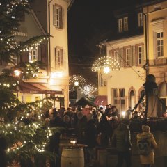 Auf dem weihnachtlich geschmückten Römerplatz in der Innenstadt versammelt sich eine große Gruppe an Adventsfreunden.